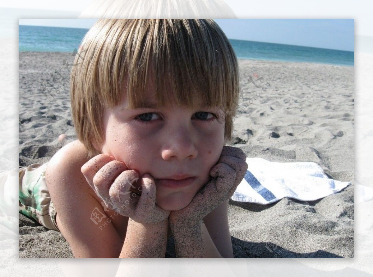 沙滩上托着下巴的男孩图片