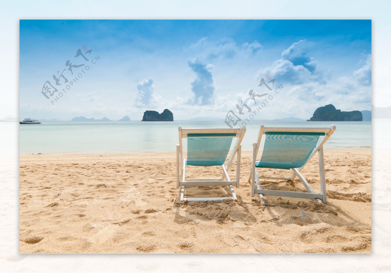 放在海边沙滩上的两把太阳椅图片