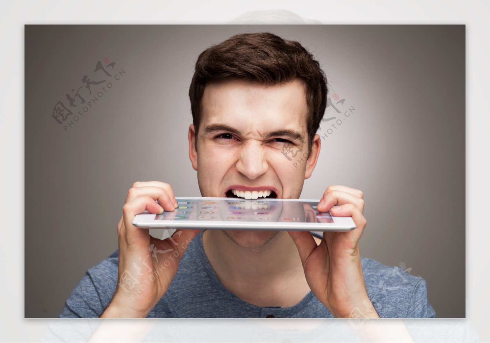 用牙齿咬平板电脑的外国男人图片