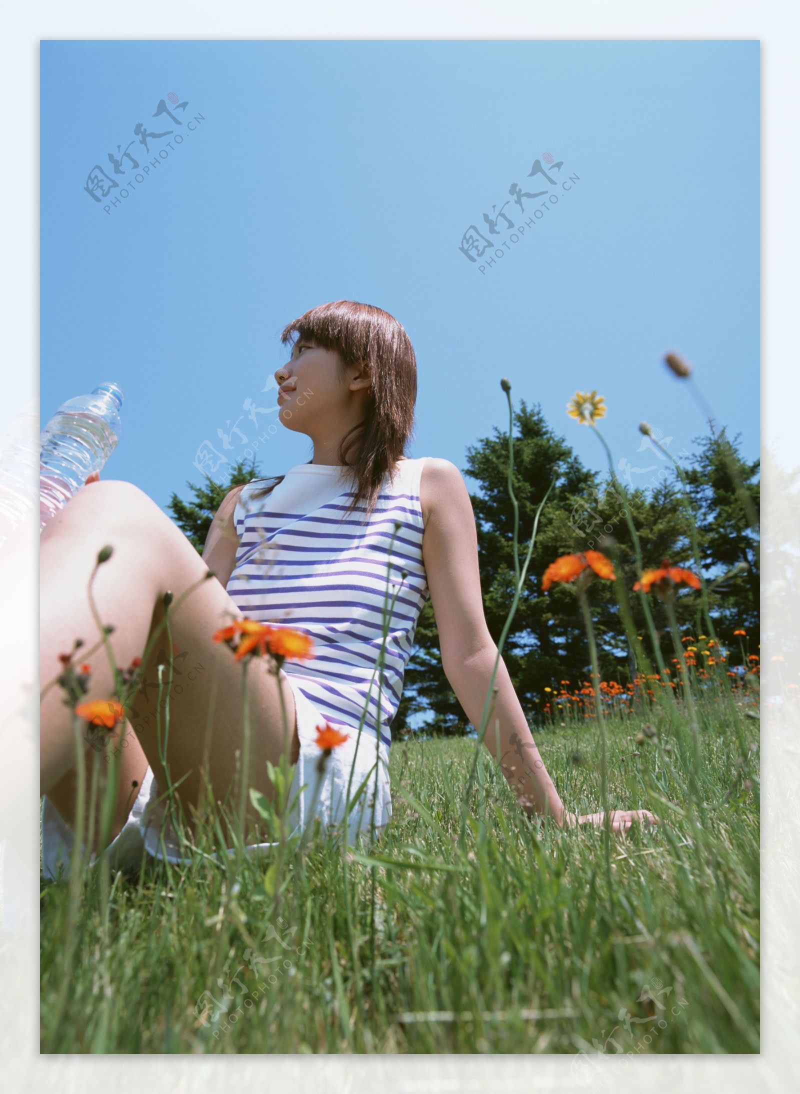 坐在草地上喝水的美女图片