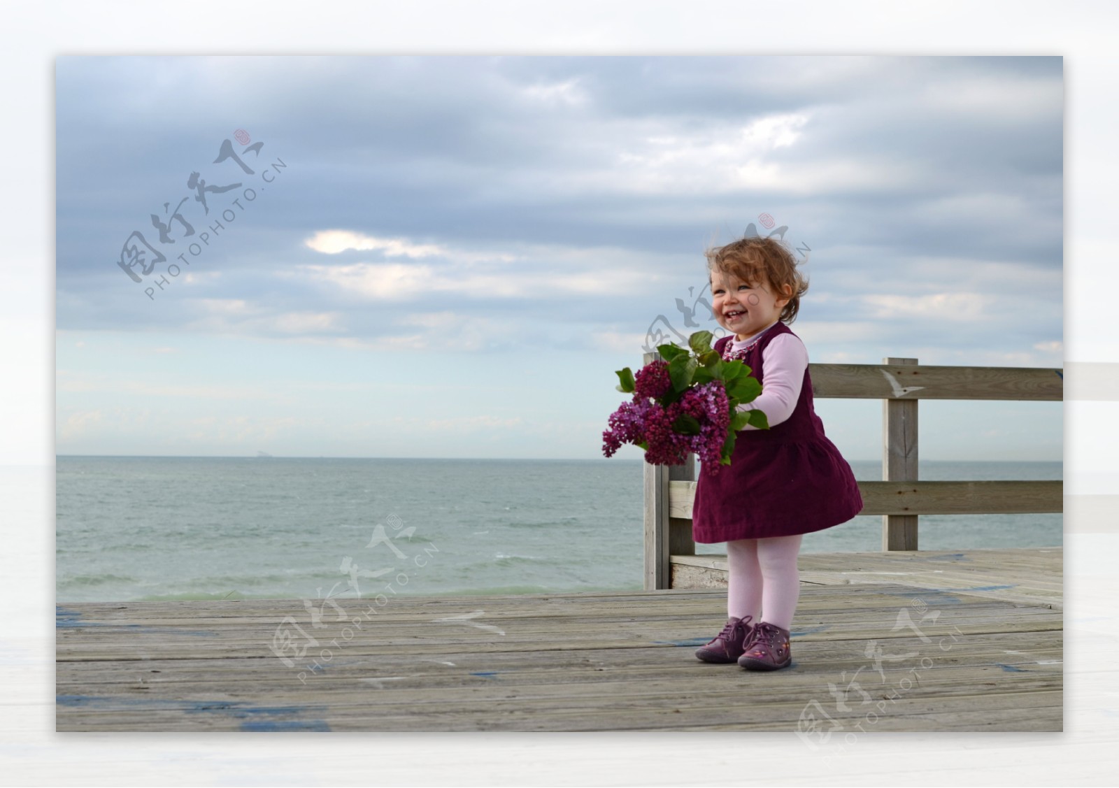 站在海边拿着鲜花的外国小女孩