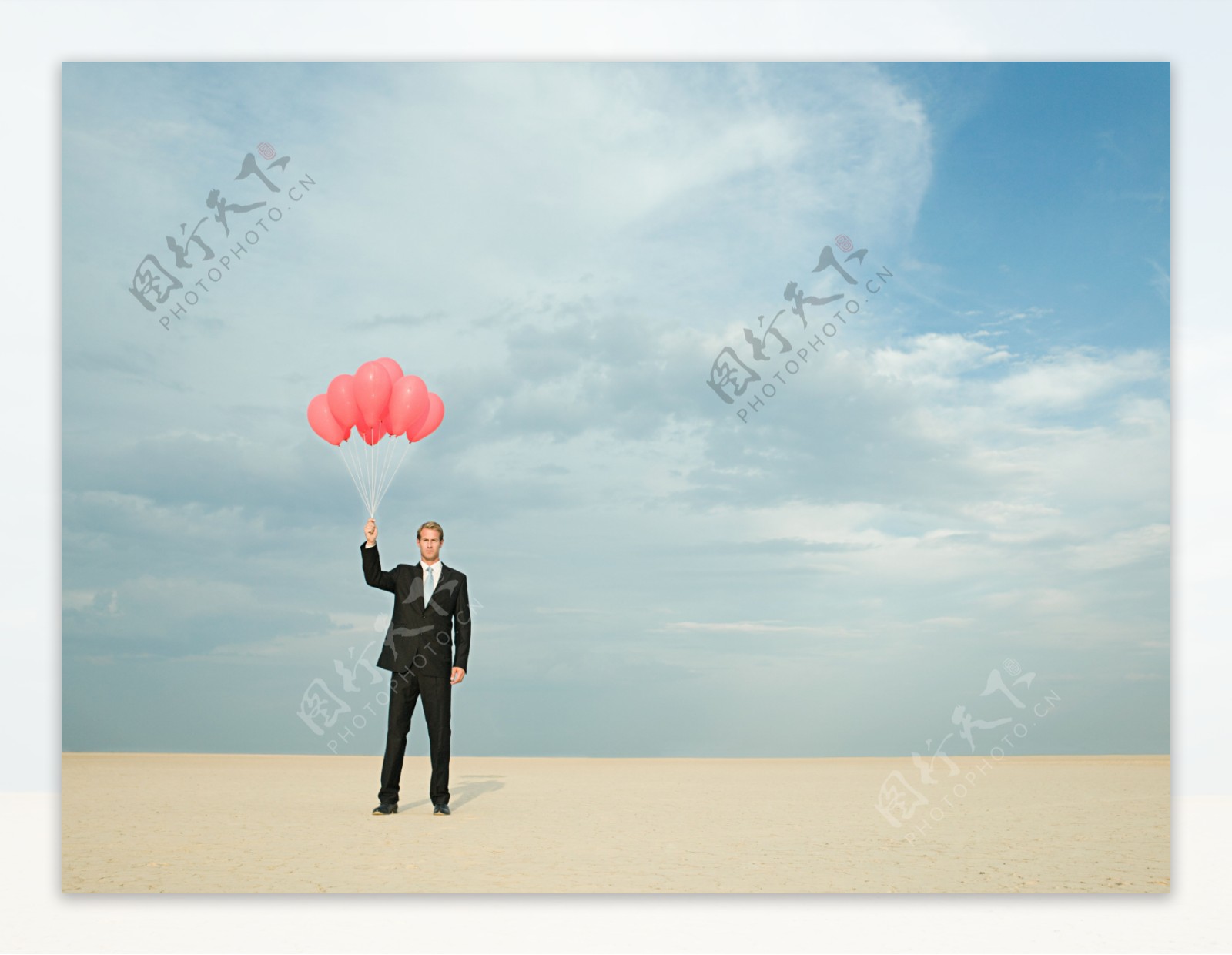 在沙漠中拿着气球的商务男人图片