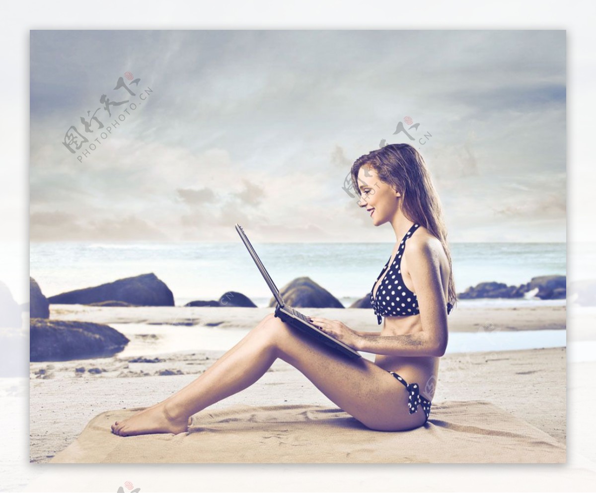 坐在沙滩上玩电脑的女人图片